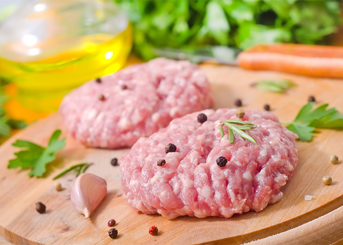 Patties of uncooked Paleo breakfast sausage seasoned with pepper and rosemary