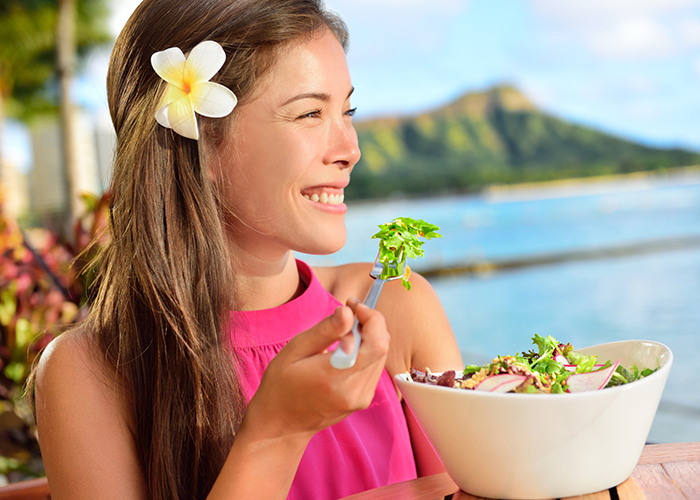 Woman by the seaside eating paleo salad