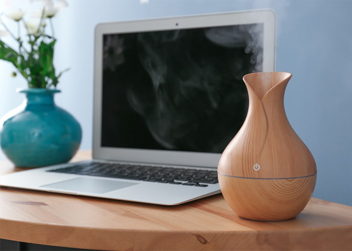A diffuser with essential oil blends for concentration and motivation next to a laptop 