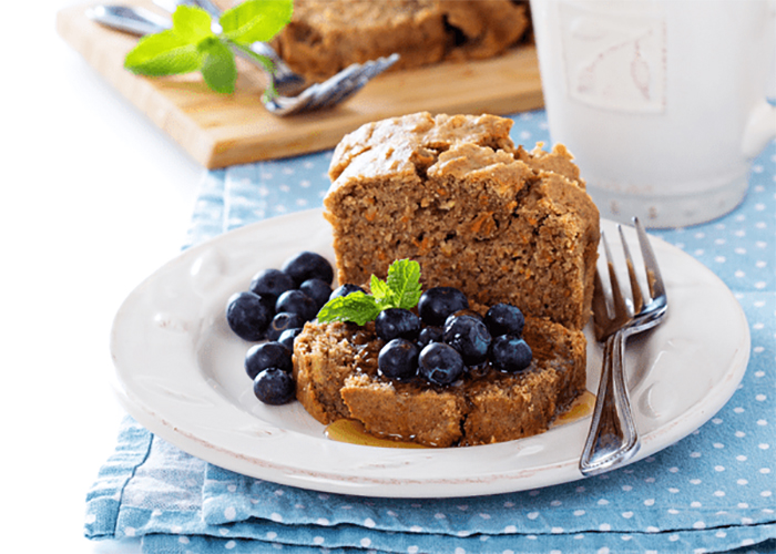 Homemade sugar-free Keto carrot cake presented with blueberries and honey on top