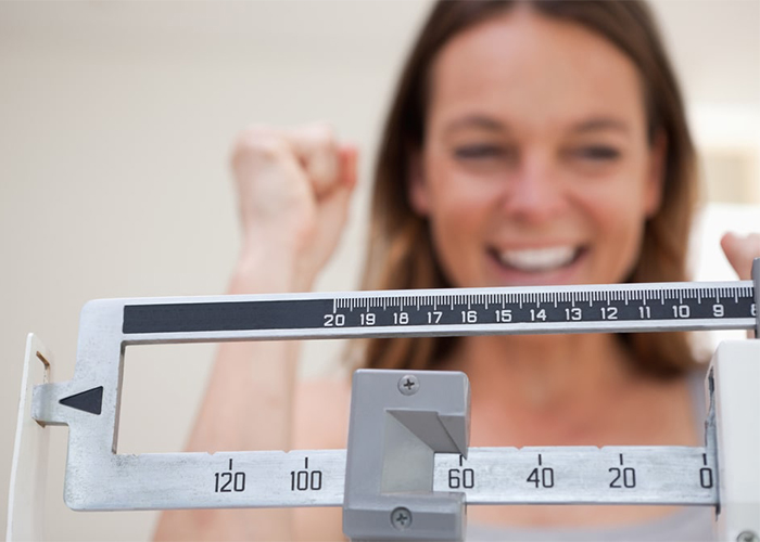 Woman on scale happy with ketosis weight loss