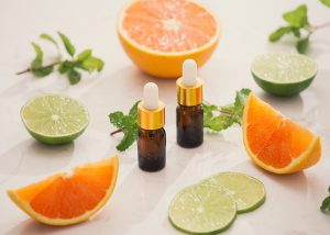 Bottles of ginger and citrus essential oil blend surrounded by cut oranges and lime