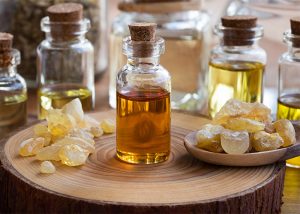 A bottle of ginger and frankincense essential oil blend next to piles of candied ginger