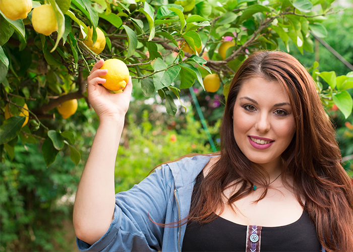 Woman in a garden holding a lemon from a lemon tree