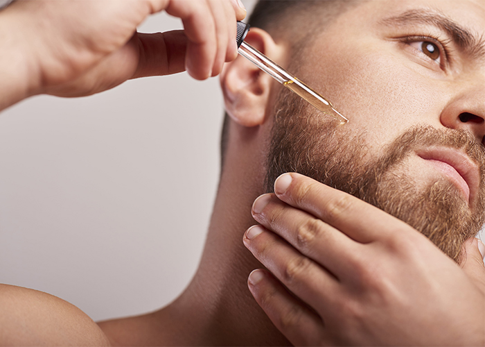 Man applying a homemade beard oil to his beard using a dropper.