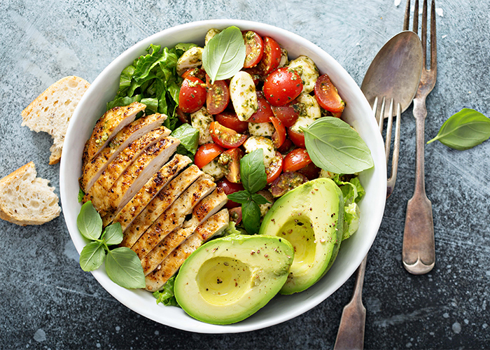 A homemade Paleo Taco Salad in a bowl with avocados, tomatoes, and chicken