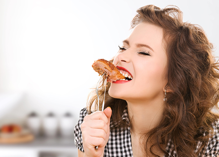 Woman smiling while biting into a Paleo steak