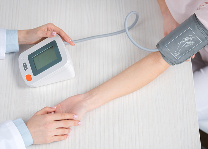 Doctor measuring a patient's blood pressure using a blood pressure machine.