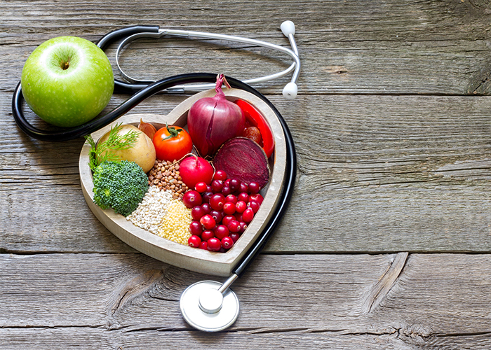 Paleo-approved fruits, vegetables, and grains in a heart shape next to a stethoscope 