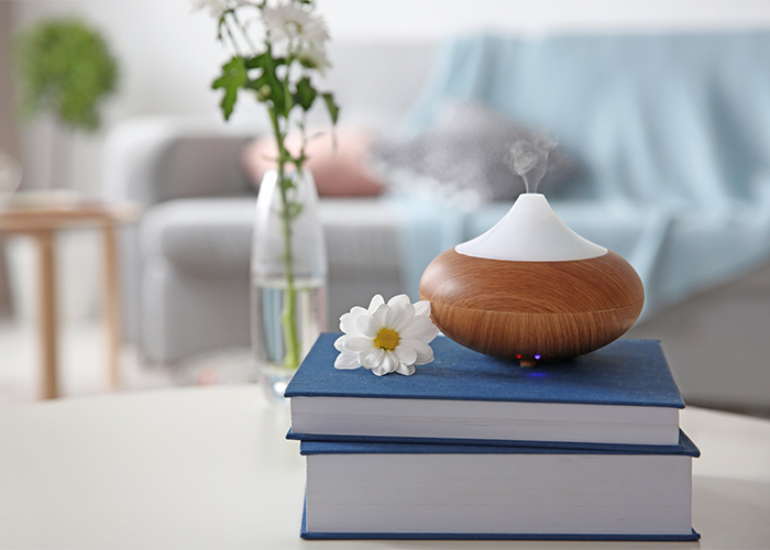 An aromatherapy diffuser with a bergamont essential oil blend for peaceful sleep on a stack of books in the lounge room
