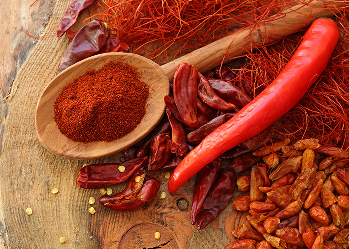 A closeup of different types of chilli, such as fresh red chili, dried chilli, and chili powder