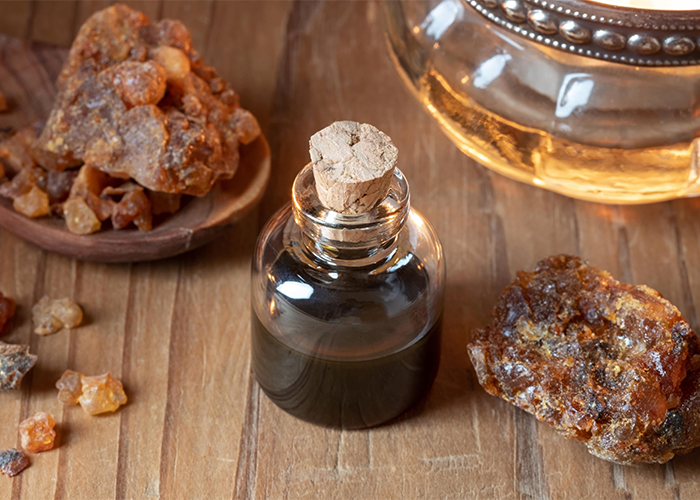 A bottle of hand-poured myrrh essential oil surrounded large and small pieces of myrrh