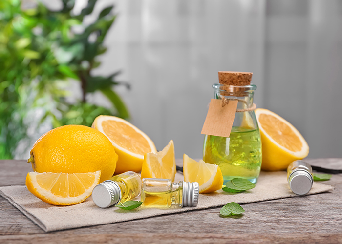 A table with bottles of lemon essential oil and cut up pieces of lemon
