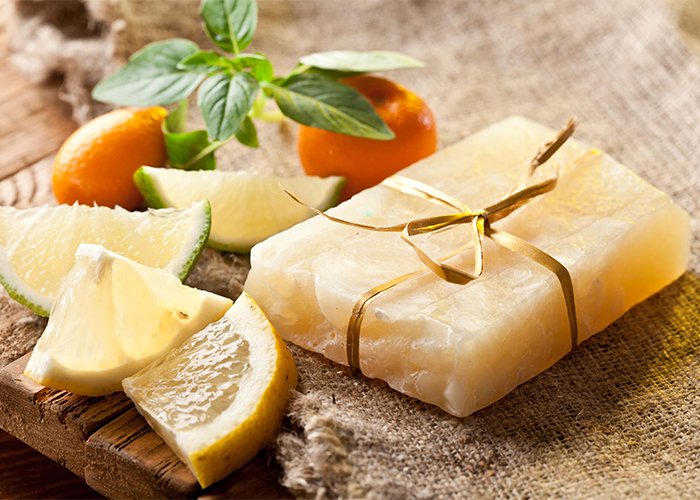 Handmade essential oil soap with lemon, bergamot and bitter orange oils  surrounded by citrus fruits
