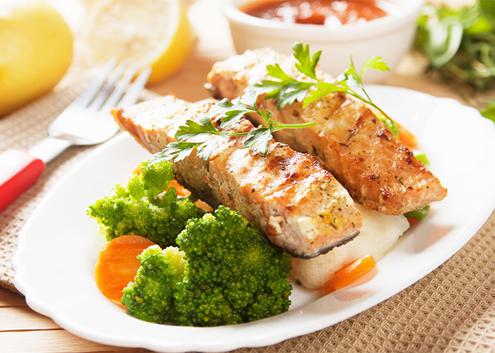 Pieces of grilled salmon and boiled vegetables presented on a plate