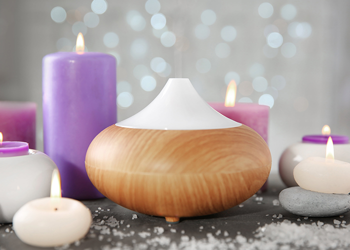 An electric essential oil diffuser surrounded by essential oil candles