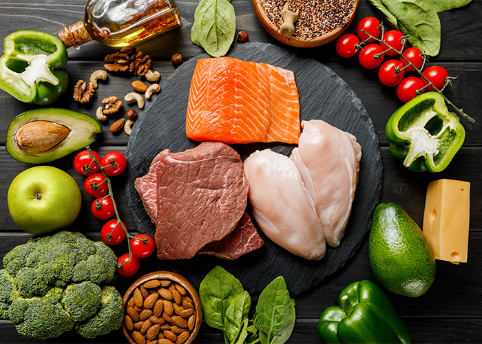 A flat lay of different keto ingredients such as meat, chicken, salmon, fruits, vegetables and nuts