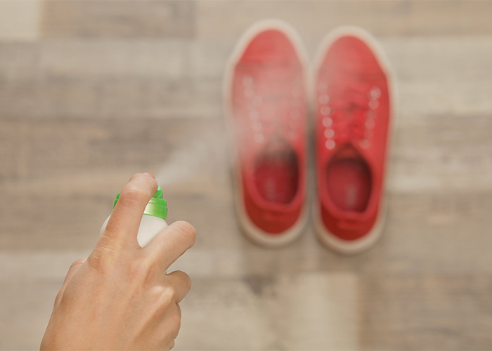 Woman spraying homemade manuka essential oil deodorizing spray on her sports shoes