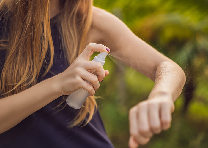 Woman spraying homemade essential oil bug spray on herself