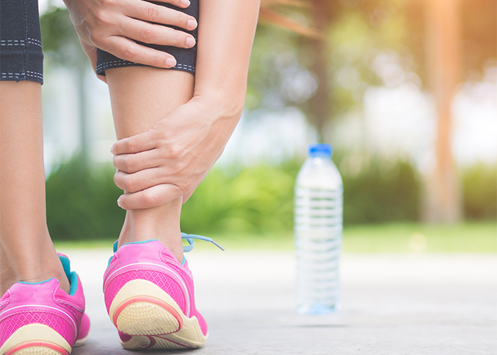 Woman grabbing her ankle in pain while on a run