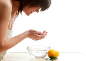 Woman washing her face with a homemade lemon essential oil cleanser