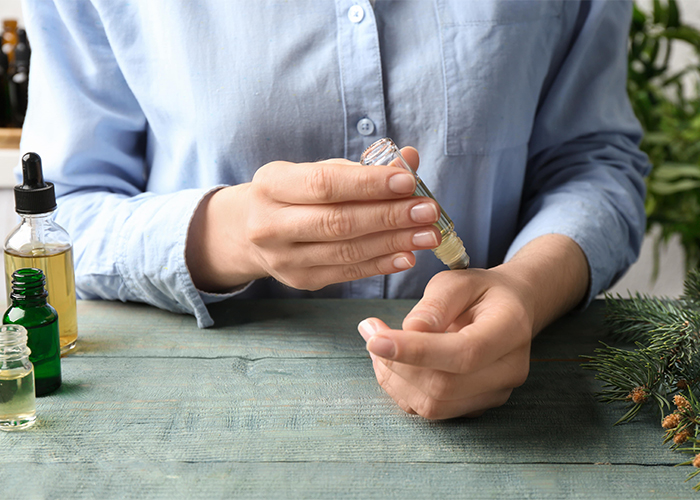 woman-applying-essential-oil-on-wrist-at-wooden-table