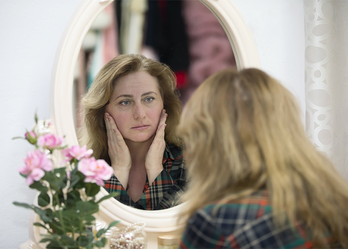 woman-looks-in-the-mirror-at-her-wrinkles