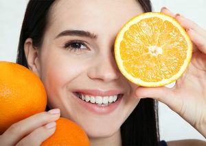 happy woman holding oranges near her face