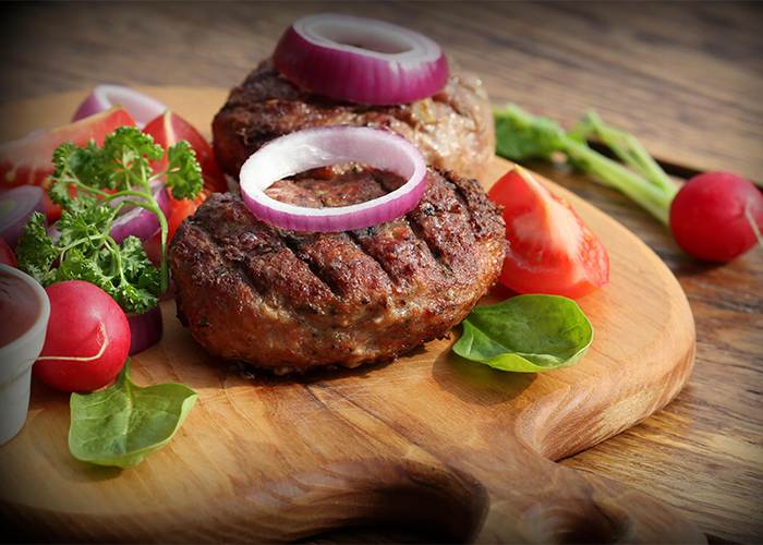 keto burger with onions and veggies on cutting board