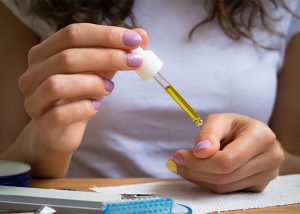 woman using orange essential oil on hand scar